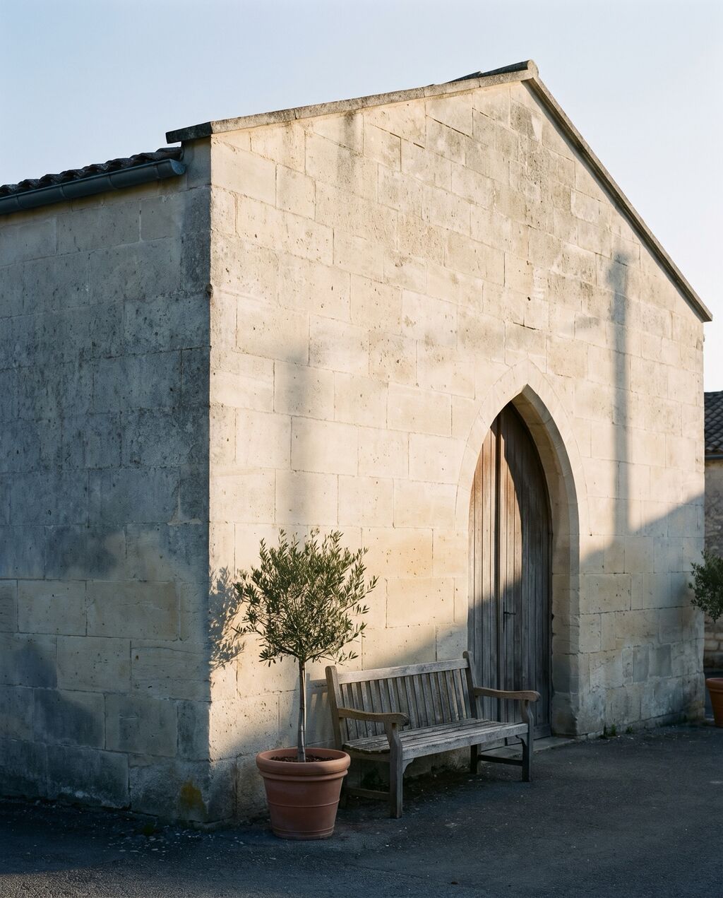 A stone building with an arched wooden door opening onto a courtyard.